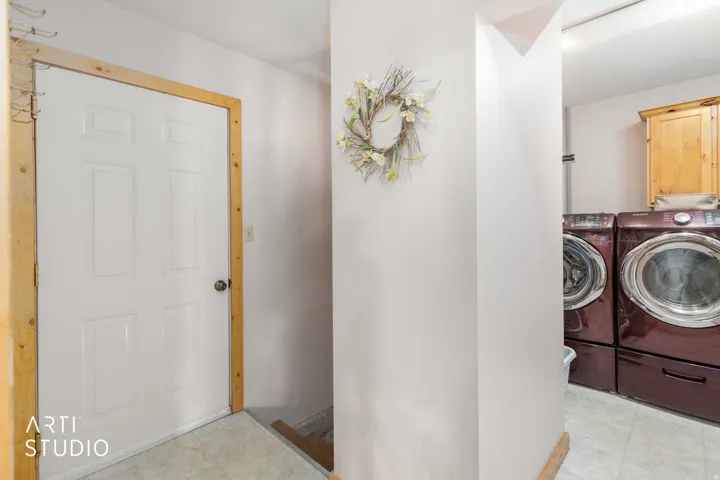 Laundry area featuring stacked appliances and light wood-finish cabinetry