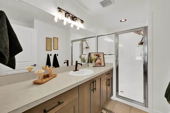Single vanity with a light-toned countertop, wood-finish cabinetry, and a bronze faucet