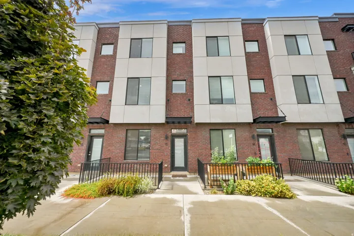 Modern facade featuring brick and paneling, multiple windows, and a paved walkway
