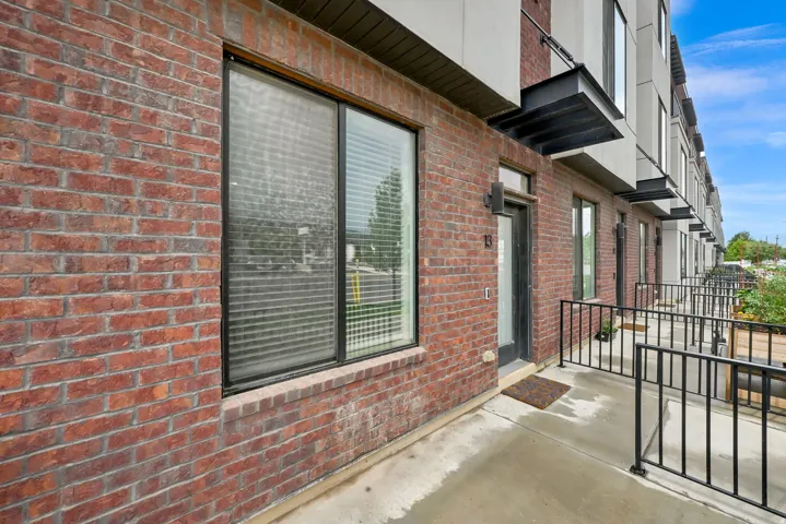 Brick exterior with large windows, covered entry, black security railings, and modern building design