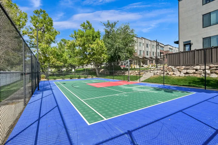 Multi-sport court with modular surfacing, basketball hoop, and chain-link fencing