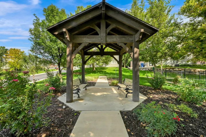 Wood-framed gazebo with an octagonal concrete base, featuring a pitched roof and decorative trusses