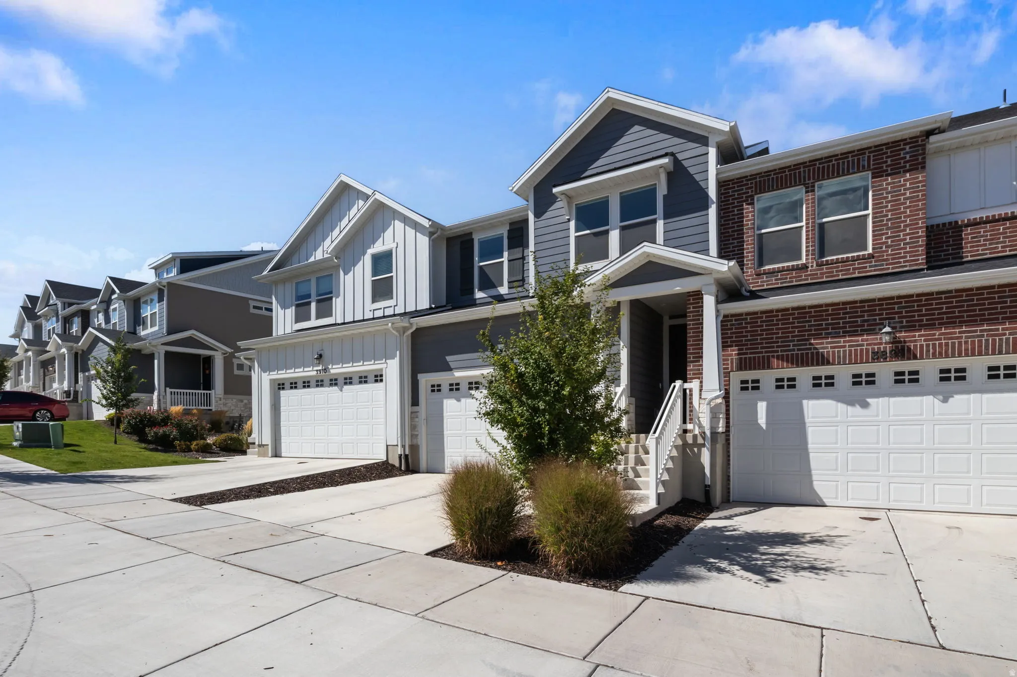 Brick and siding exterior, two-car garage, concrete driveway, covered porch entry, and exterior lighting fixtures