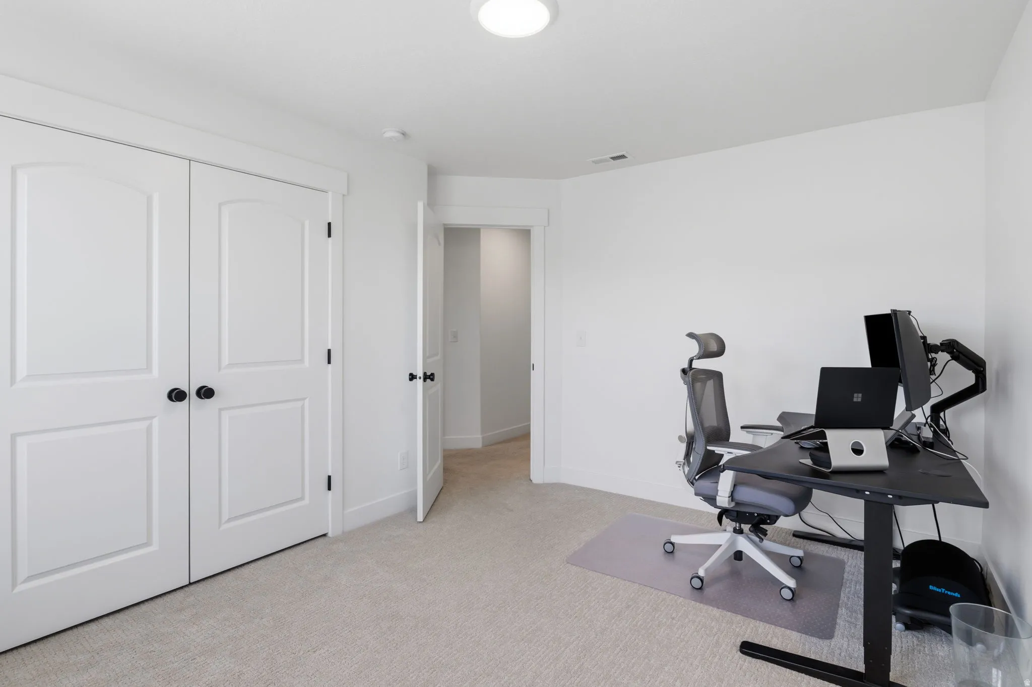 Neutral tone interior with light colored carpeting, white walls, and a recessed ceiling light fixture