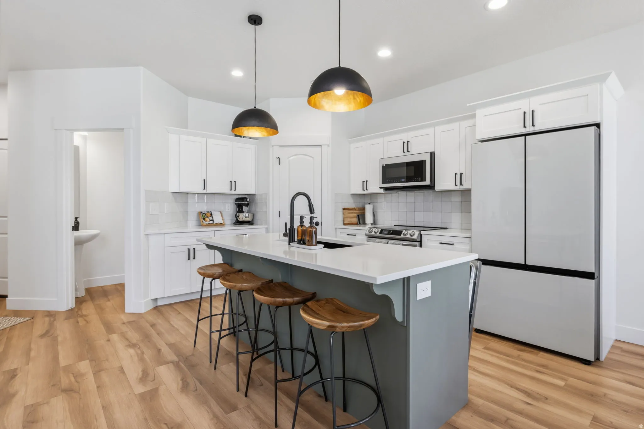 Modern kitchen featuring a central island with countertop, white cabinetry, stainless steel appliances, and wood-finish flooring