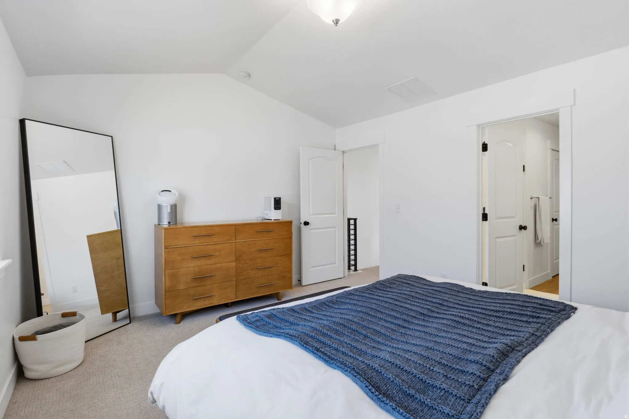 Vaulted ceiling, ceiling-mounted light fixture, white walls, carpeted flooring, white trim