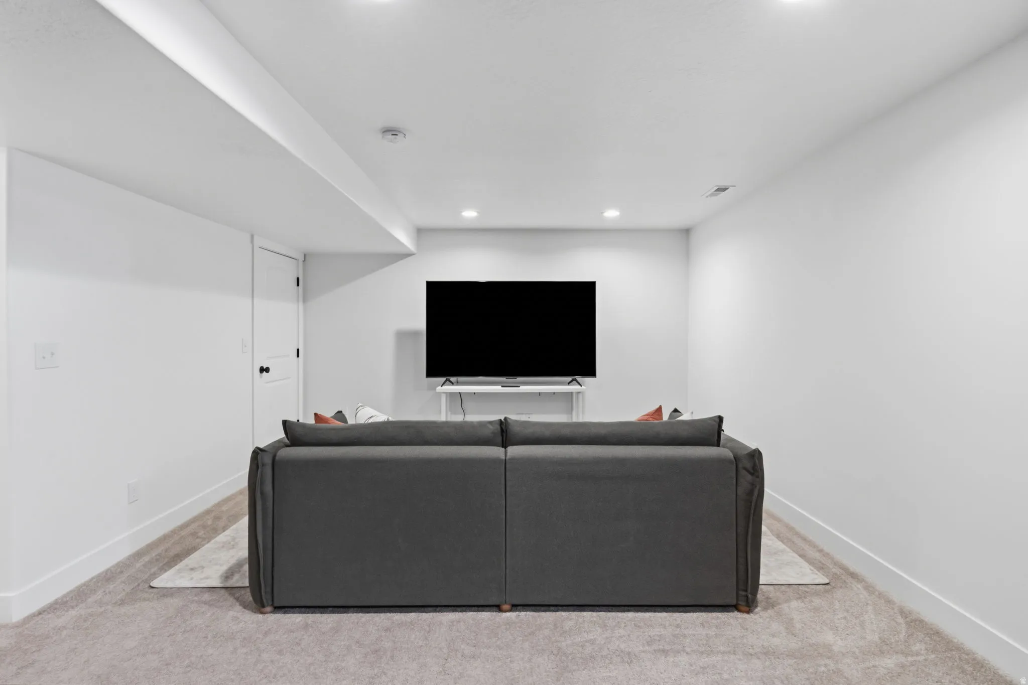 Recessed lighting throughout, light-toned carpeted flooring, and white walls