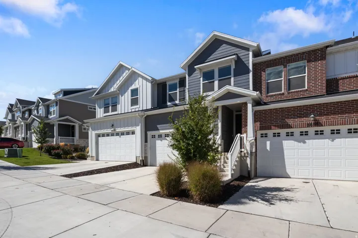 Brick and siding exterior, two-car garage, concrete driveway, covered porch entry, and exterior lighting fixtures
