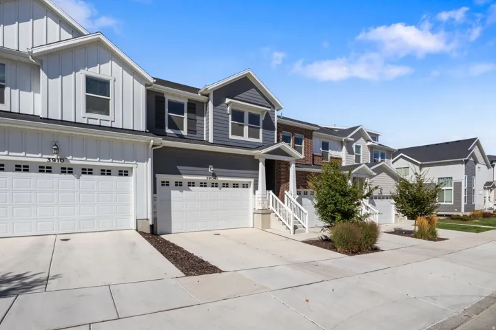 Contemporary townhomes featuring a combination of vertical and horizontal siding, attached two-car garages, mature landscaping, and concrete driveways