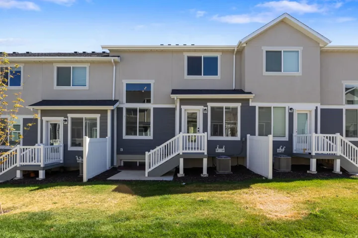 Rear exterior featuring two decks with white railings, a concrete patio, and a grass lawn