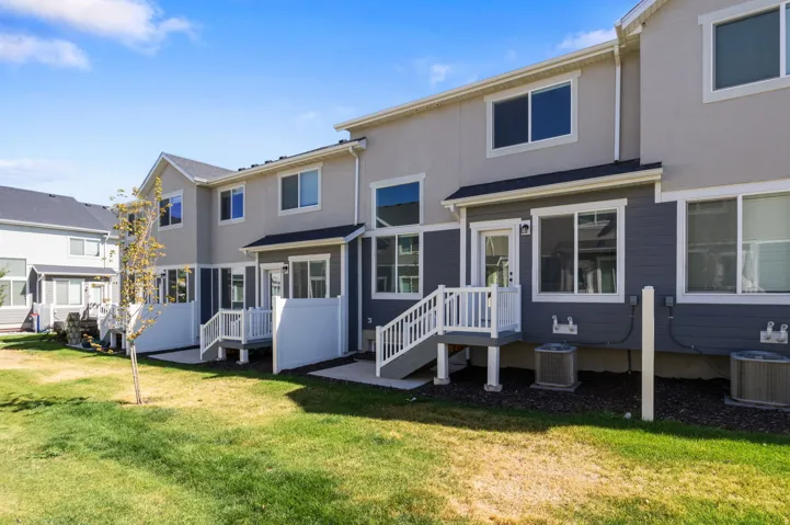 Multi-level townhome exterior featuring light gray stucco and dark gray siding