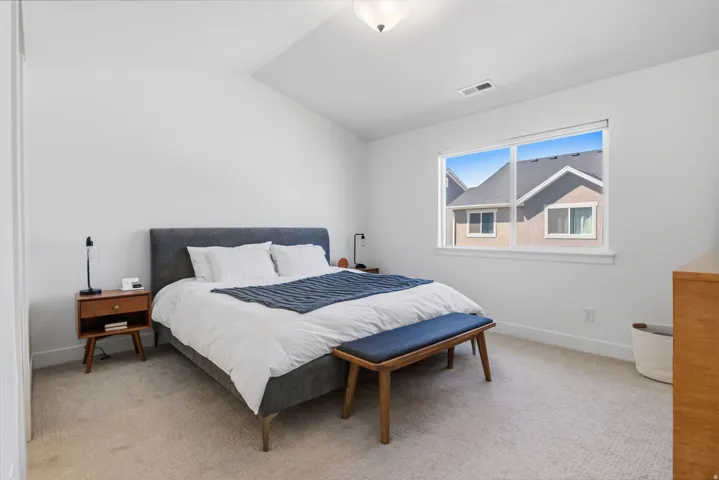Neutral carpeted flooring, white painted walls, and a single window with white trim