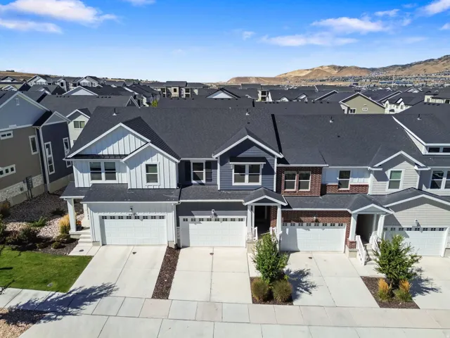 Townhome exterior featuring varied siding materials, attached garages, covered entryways, and concrete driveways