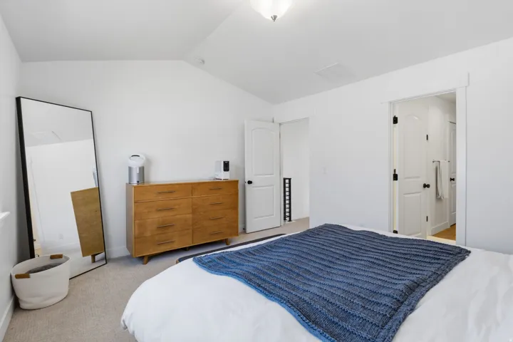 Vaulted ceiling, ceiling-mounted light fixture, white walls, carpeted flooring, white trim