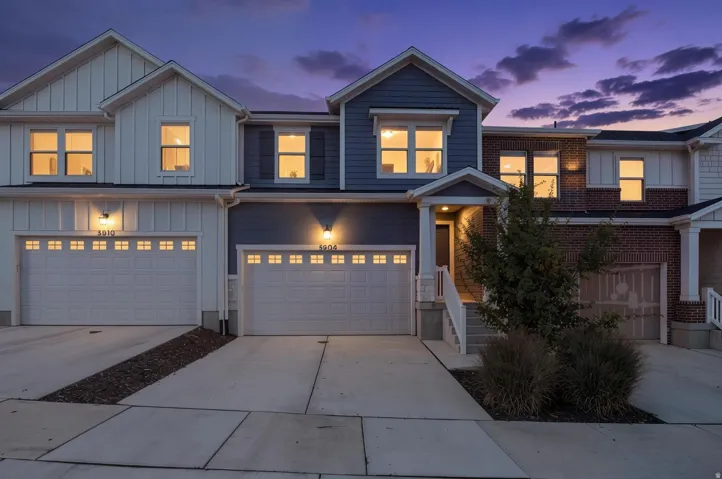 Contemporary multi-story facade featuring mixed material siding, integrated garage, and a covered entry with steps