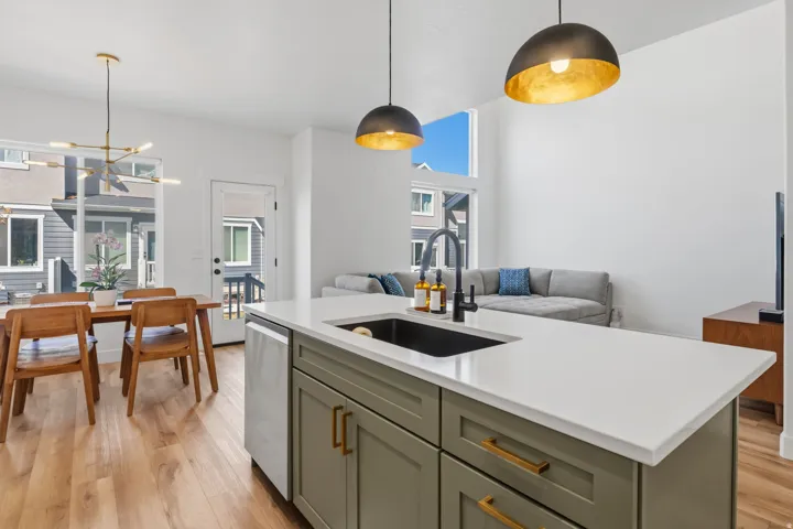Kitchen island with an undermount sink and matte black faucet, light wood-finish flooring, a contemporary chandelier, and high ceilings