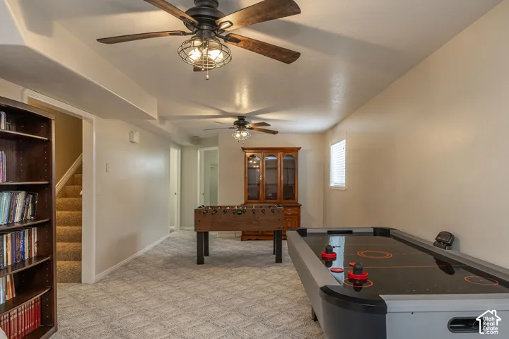 Ceiling fans with integrated lighting, window, patterned carpet flooring.
