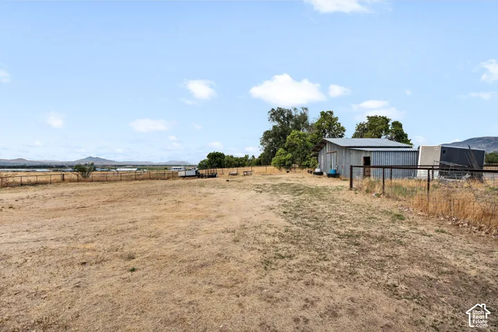 Expansive open field with a metal-sided barn and perimeter fencing.