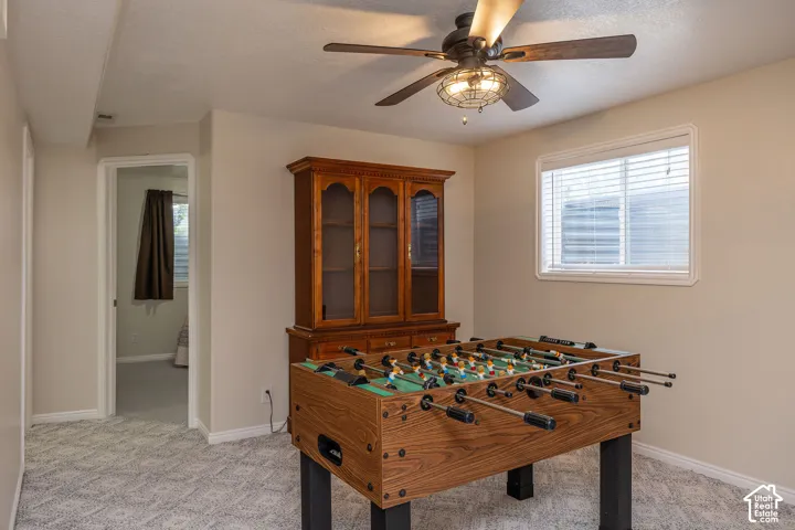 Recessed window, patterned carpet flooring, ceiling fan with integrated lighting, and neutral wall paint.