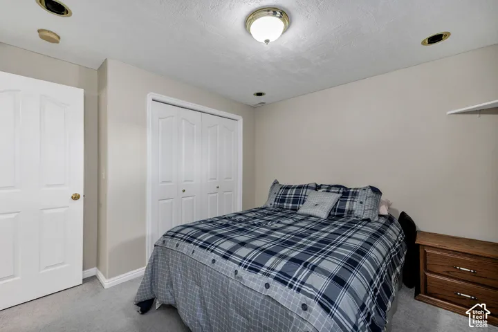 Neutral wall paint, recessed lighting, central ceiling light fixture, white bi-fold closet doors, and carpet flooring.