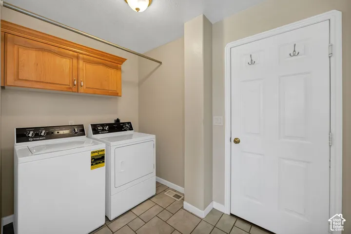 Laundry area featuring overhead cabinetry, a clothing rod, and tile flooring