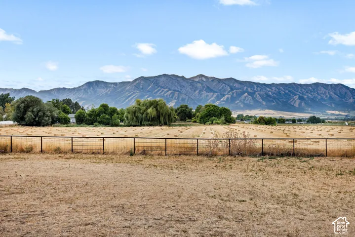 Expansive property featuring a metal fence, open fields, and mountain backdrop.