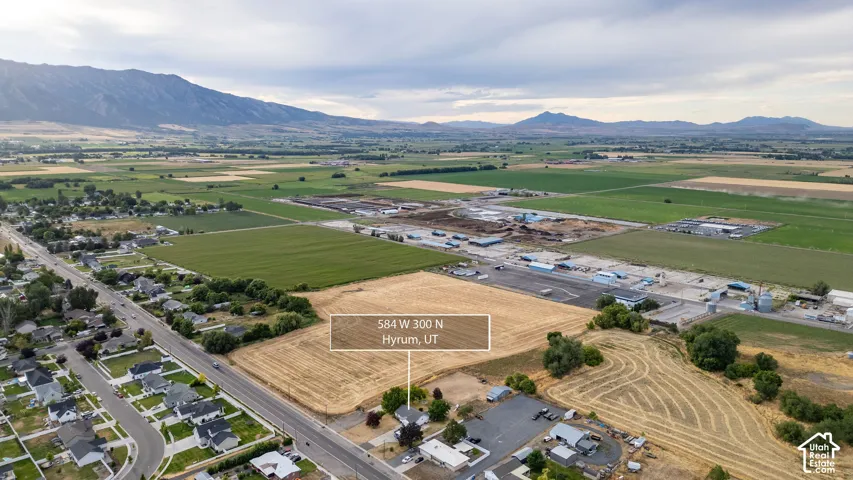 Expansive land parcel with surrounding agricultural fields, distant mountains, and nearby residential developments.