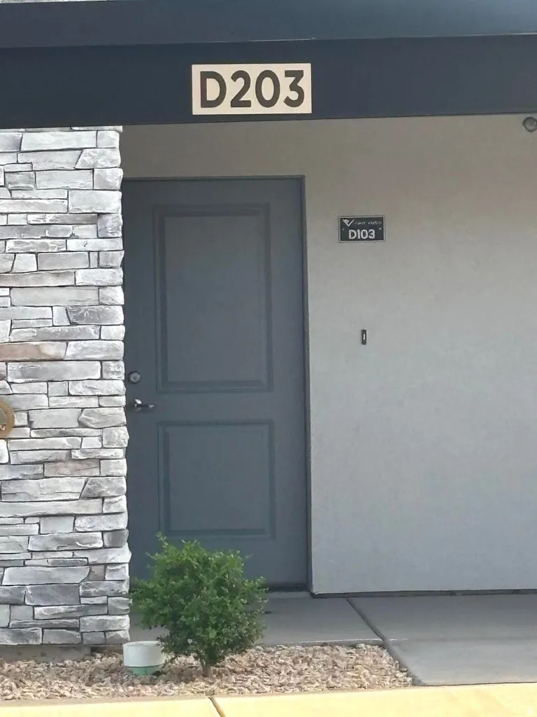 Stacked stone exterior accent, paneled entry door, concrete pathway, and decorative gravel landscaping