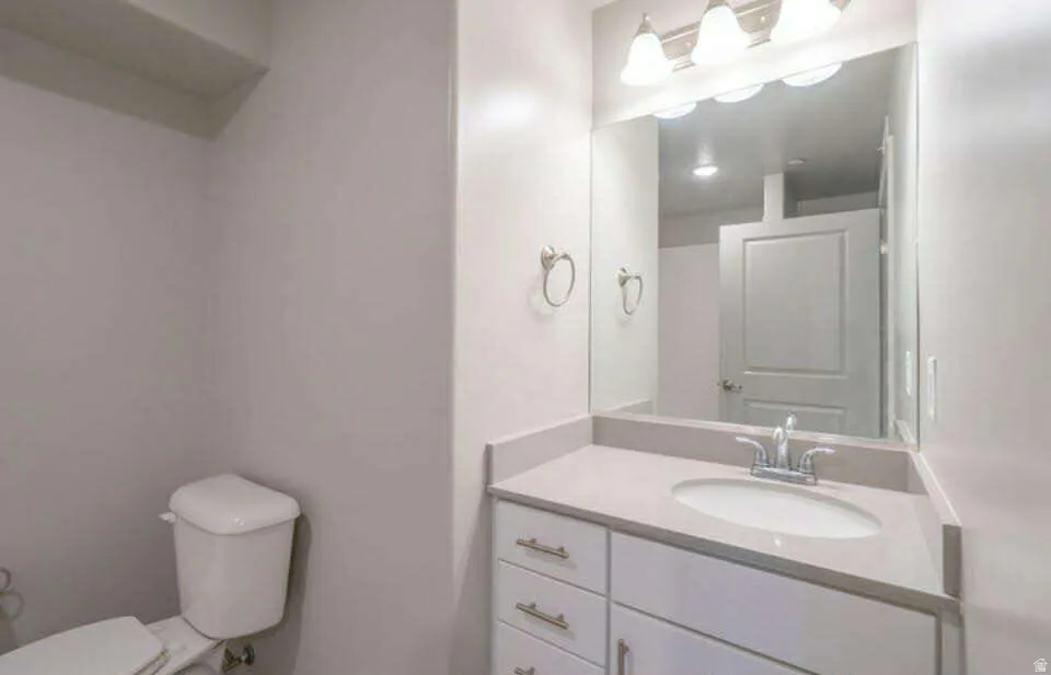 White vanity with brushed nickel hardware, light-toned countertop, and undermount sink
