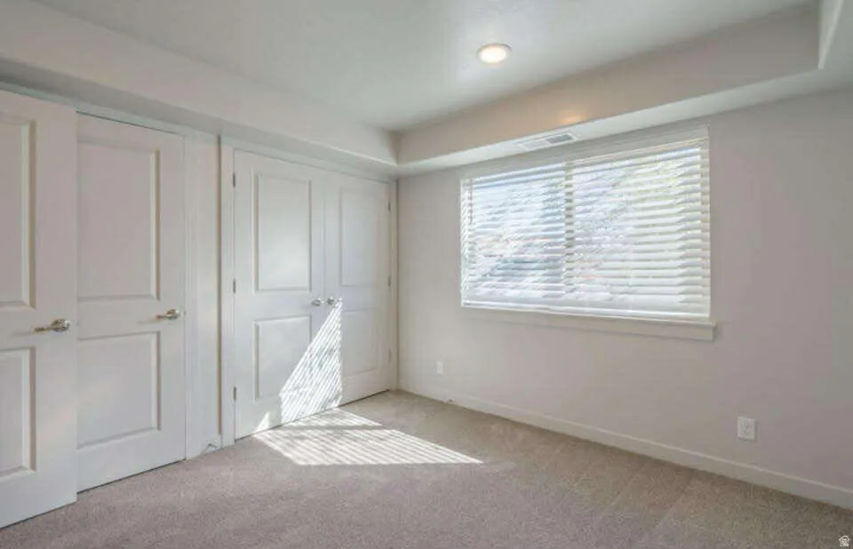 Recessed ceiling lighting, window with blinds, panel doors, and carpet flooring