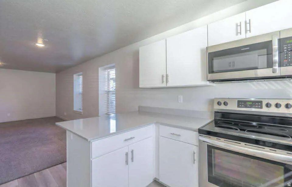 Contemporary kitchen featuring stainless steel appliances, white cabinetry, and light-toned countertops