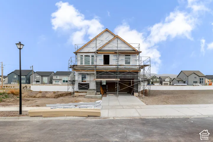 Two-story residential structure featuring a gable roof, integrated garage, concrete driveway, and front entryway
