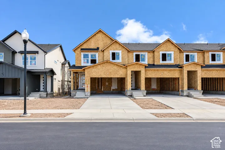 Multi-unit residential structure featuring wood-sheathed exterior, shingled roofing, concrete driveways, and covered entryways