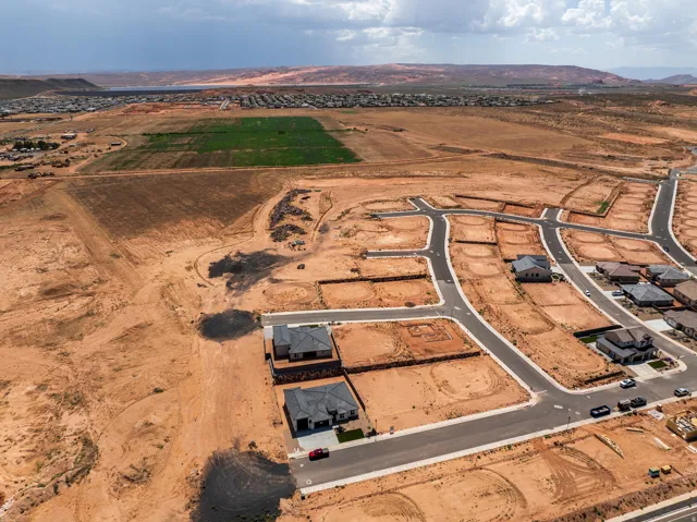 Developing residential neighborhood with established roads and visible red rock formations in the distance