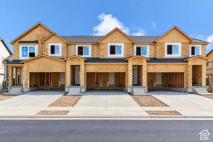 Multi-unit residential structure featuring wood-sheathed exterior, asphalt shingle roofing, integrated garage bays, and concrete driveways