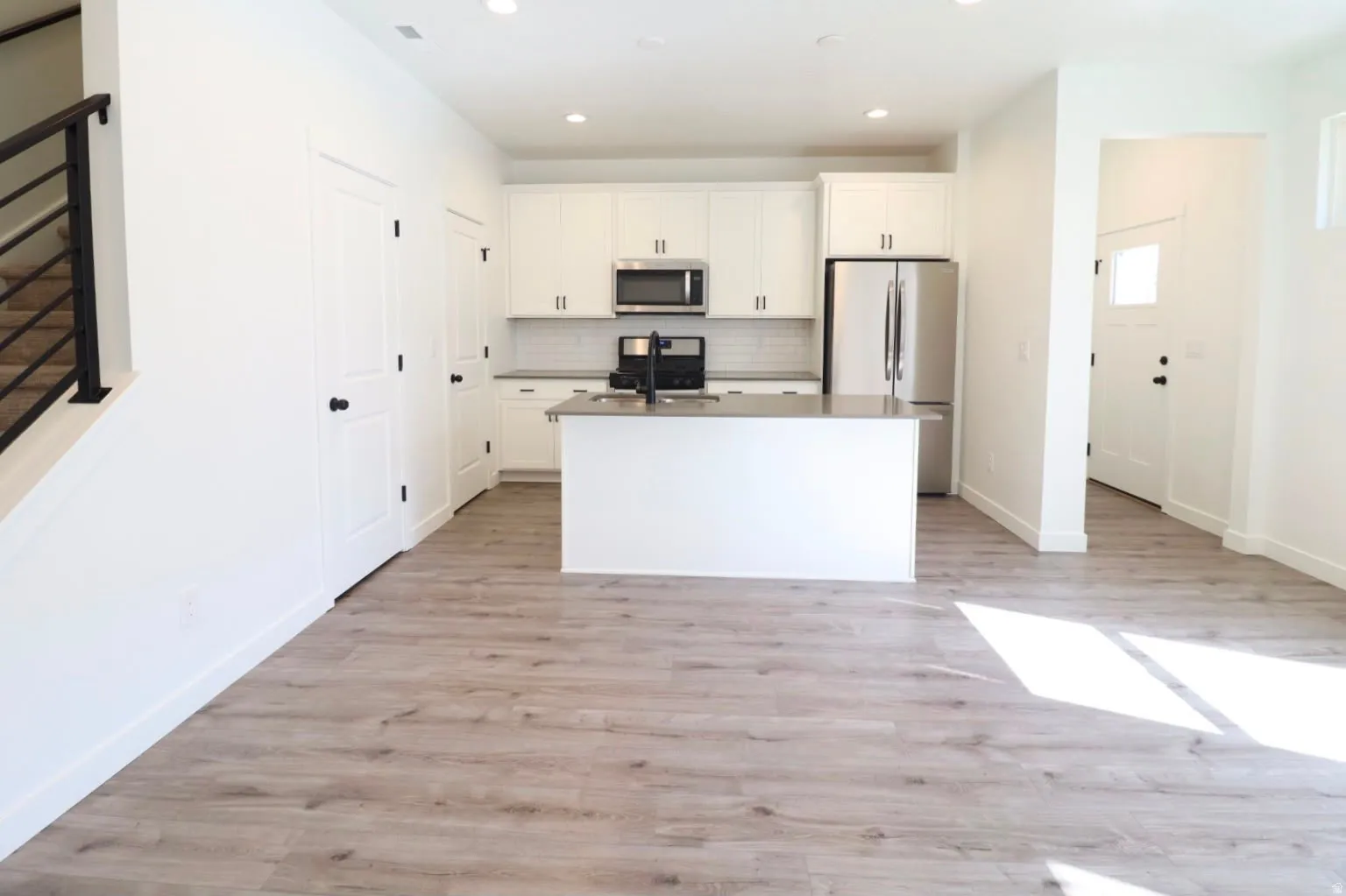 Kitchen featuring white cabinetry, stainless steel appliances, a kitchen island, and light wood-finish flooring