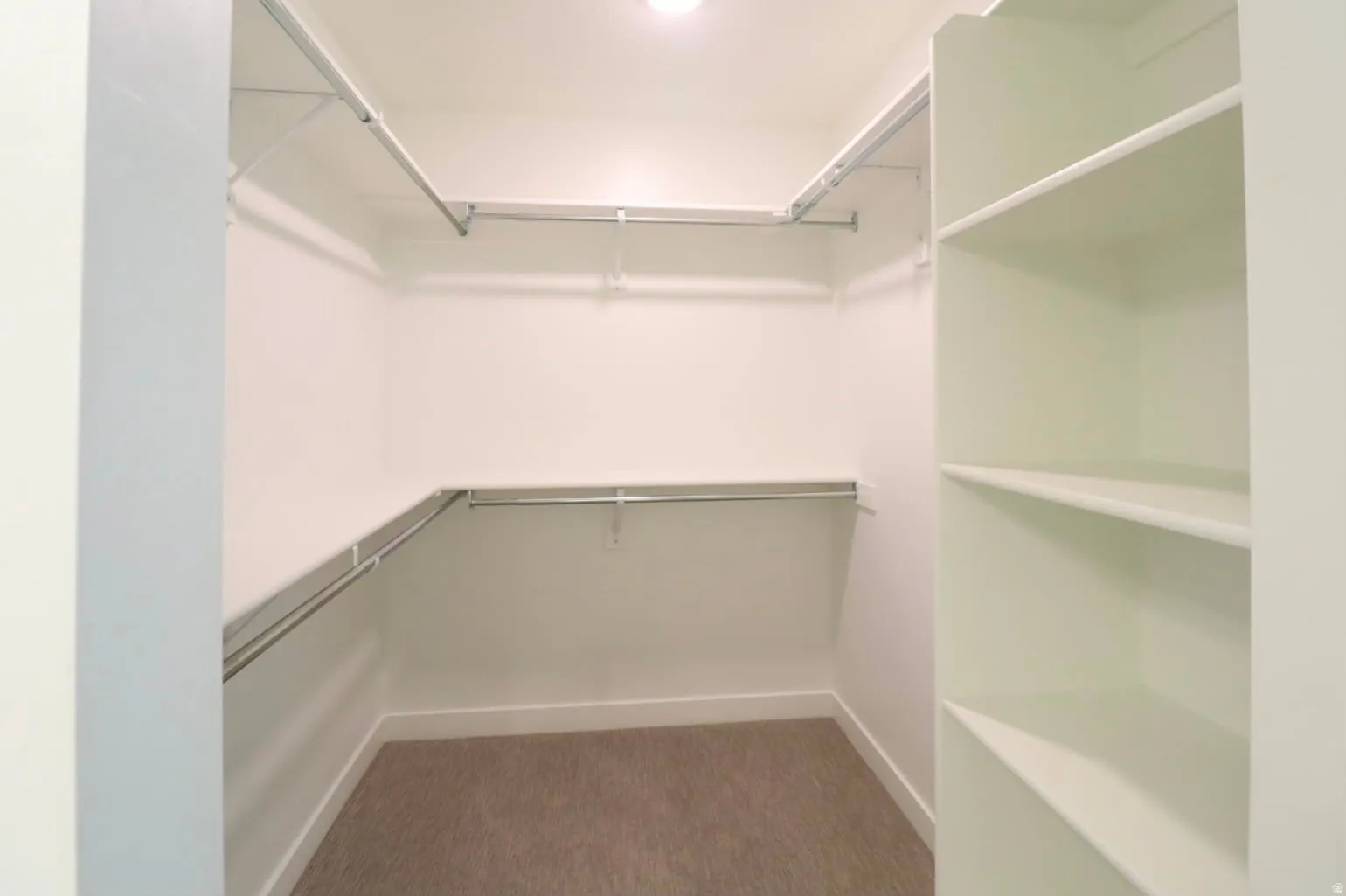 Walk-in closet with carpet flooring, built-in shelving, and multiple hanging rods