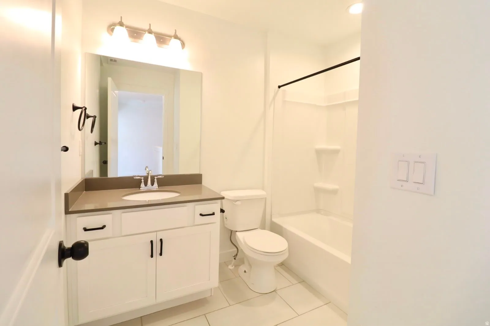 White vanity with dark hardware, undermount sink, and light-colored countertop