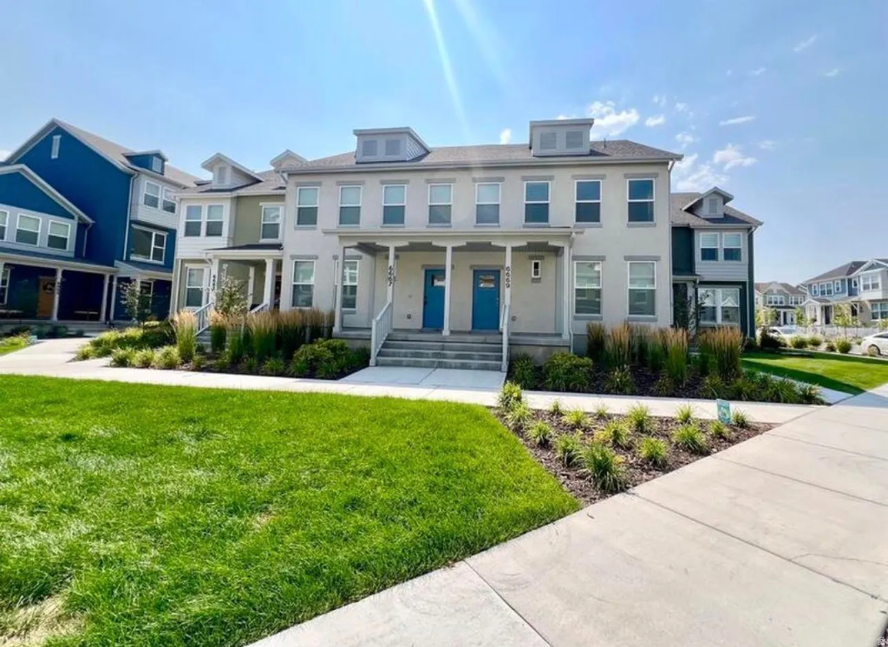 Stucco exterior with multiple windows, covered front entrance, and contrasting blue entry door