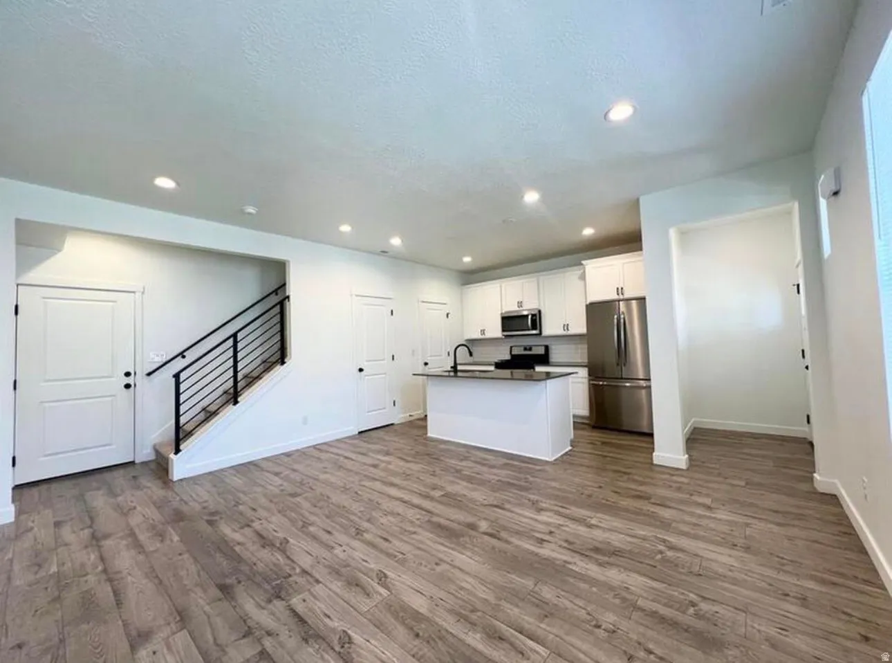 Open-concept living area featuring wood-finish flooring, recessed lighting, and a modern kitchen