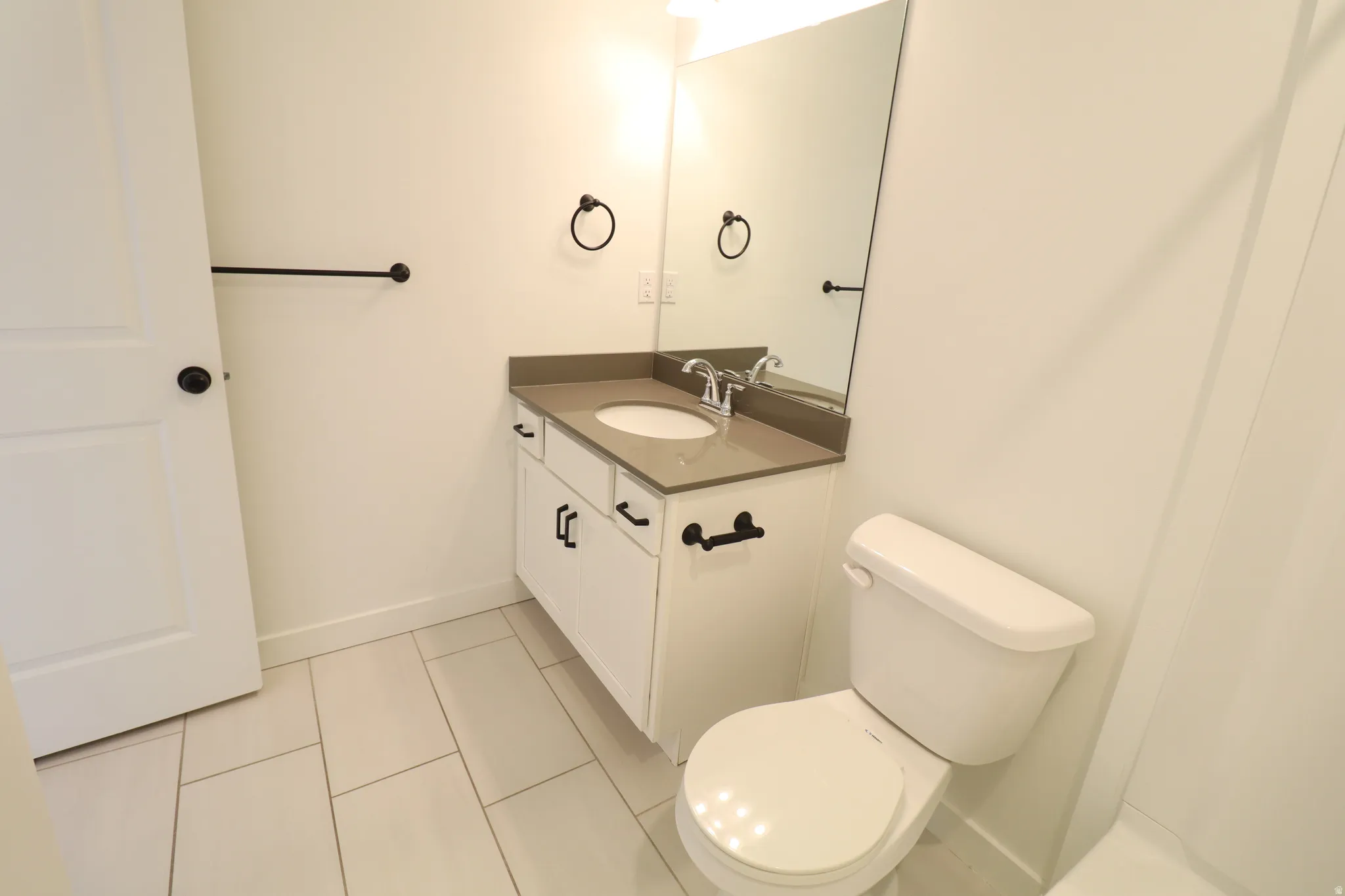 White vanity with dark hardware, undermount sink, and a countertop