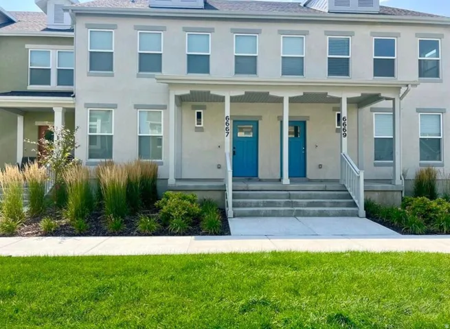 Multi-story stucco exterior with dormer windows and covered porch entries