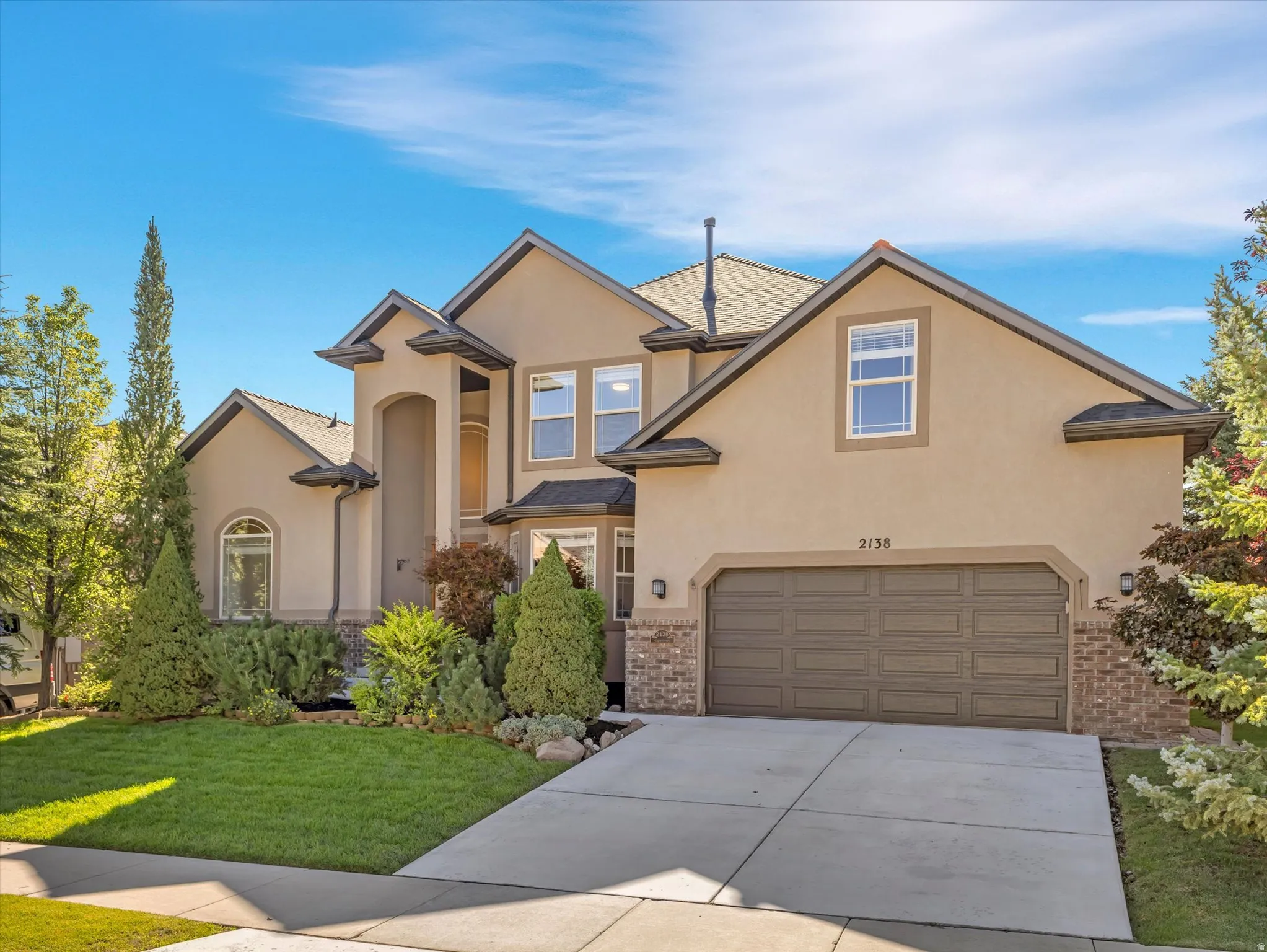 Stucco exterior with brick detailing, multi-pane windows, a recessed entry, and an integrated garage
