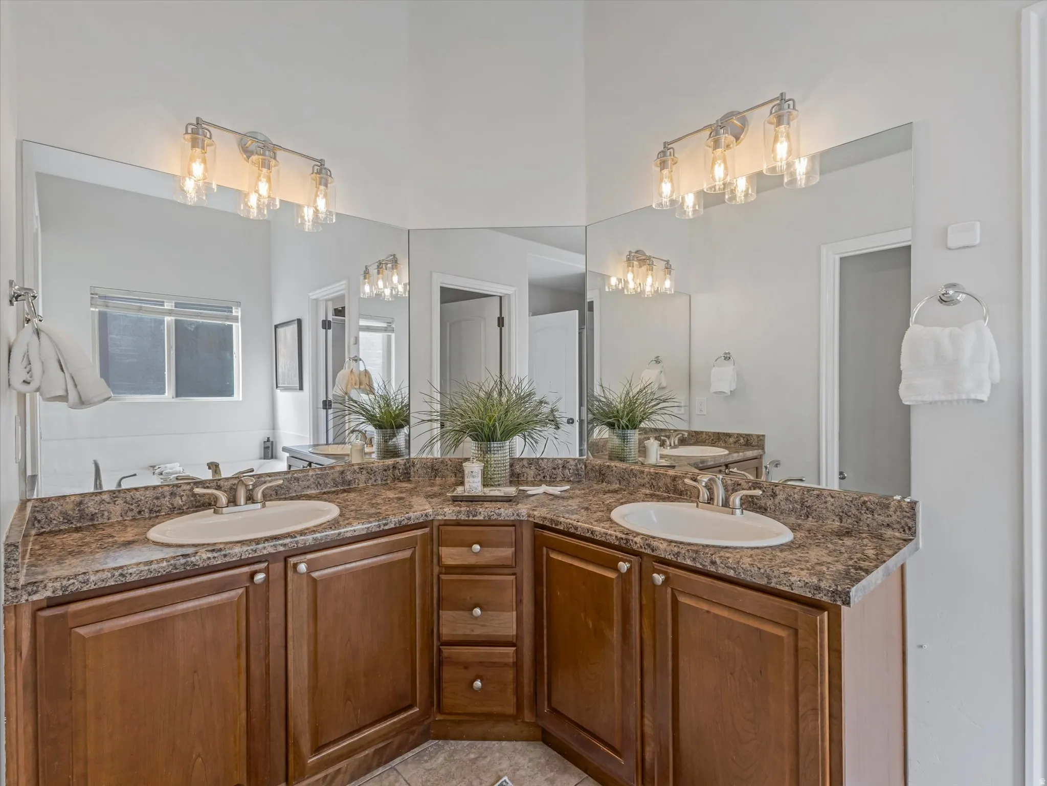 Dual vanity with wood-finish cabinetry, integrated sinks, and brown patterned countertops