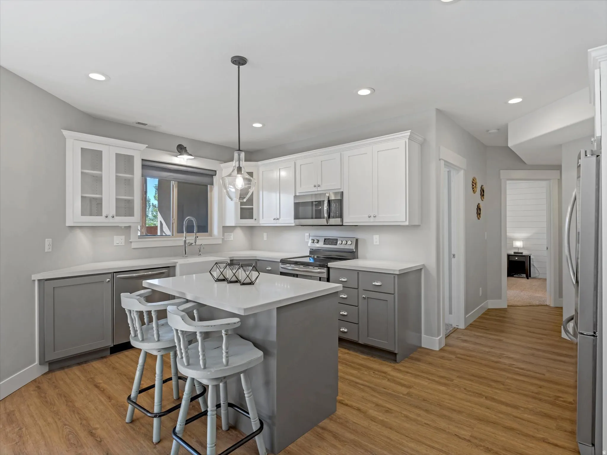 Kitchen featuring an island with stone countertop, wood-finish flooring, two-tone cabinetry, and recessed lighting