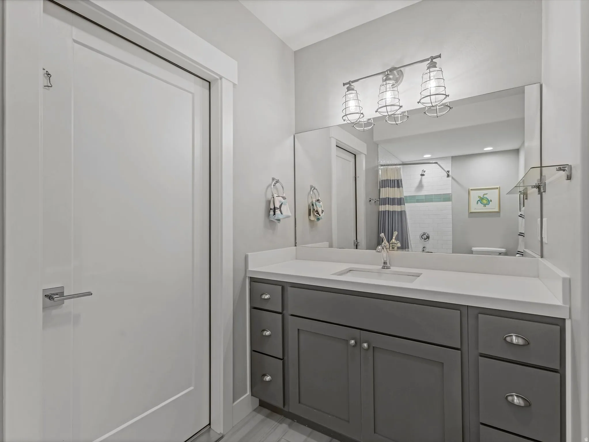 Bathroom featuring a single vanity with gray cabinetry, a white countertop, and an undermount sink