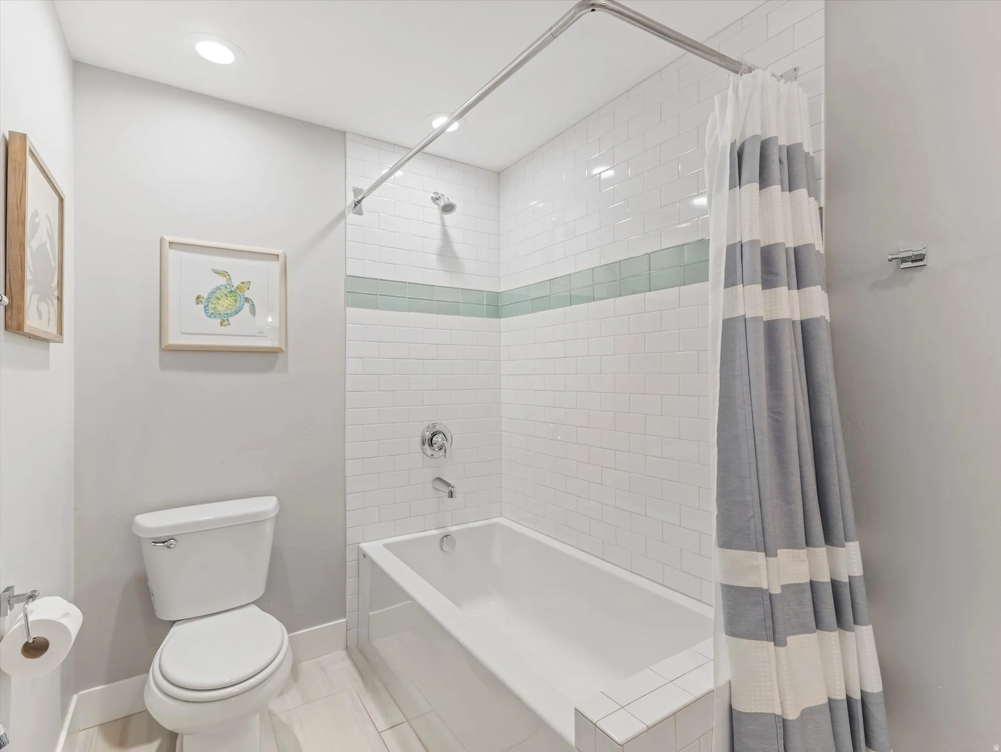 Recessed lighting, white subway tile surround, integrated bathtub, and a modern toilet