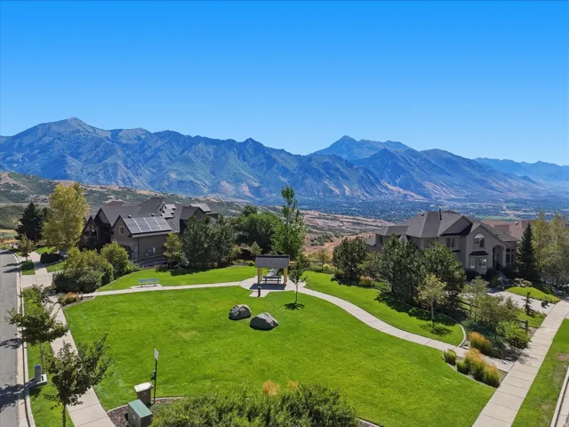 Expansive green space featuring a paved walkway, mature trees, and a mountain backdrop