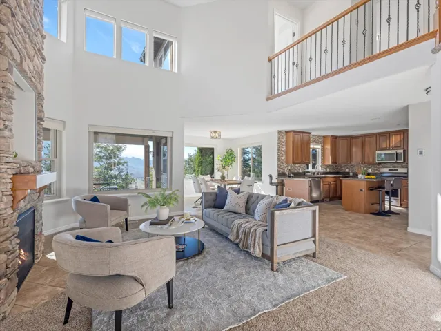 Two-story living area featuring a stone fireplace, high ceilings, and an open balcony