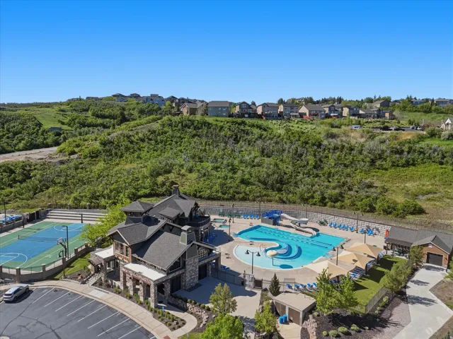 Recreational complex featuring a large swimming pool with water slide, a separate wading pool, a full basketball court, and a clubhouse with stone and siding exterior